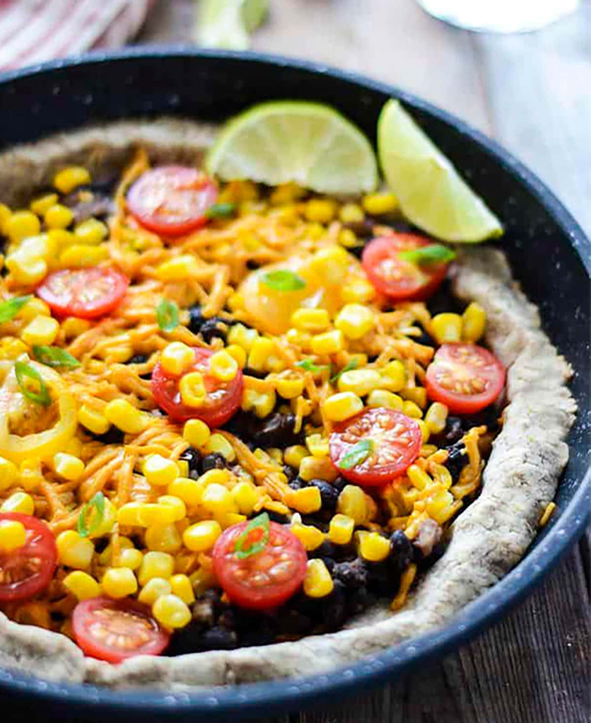 Black bean pizza in a cast iron skillet on wooden board