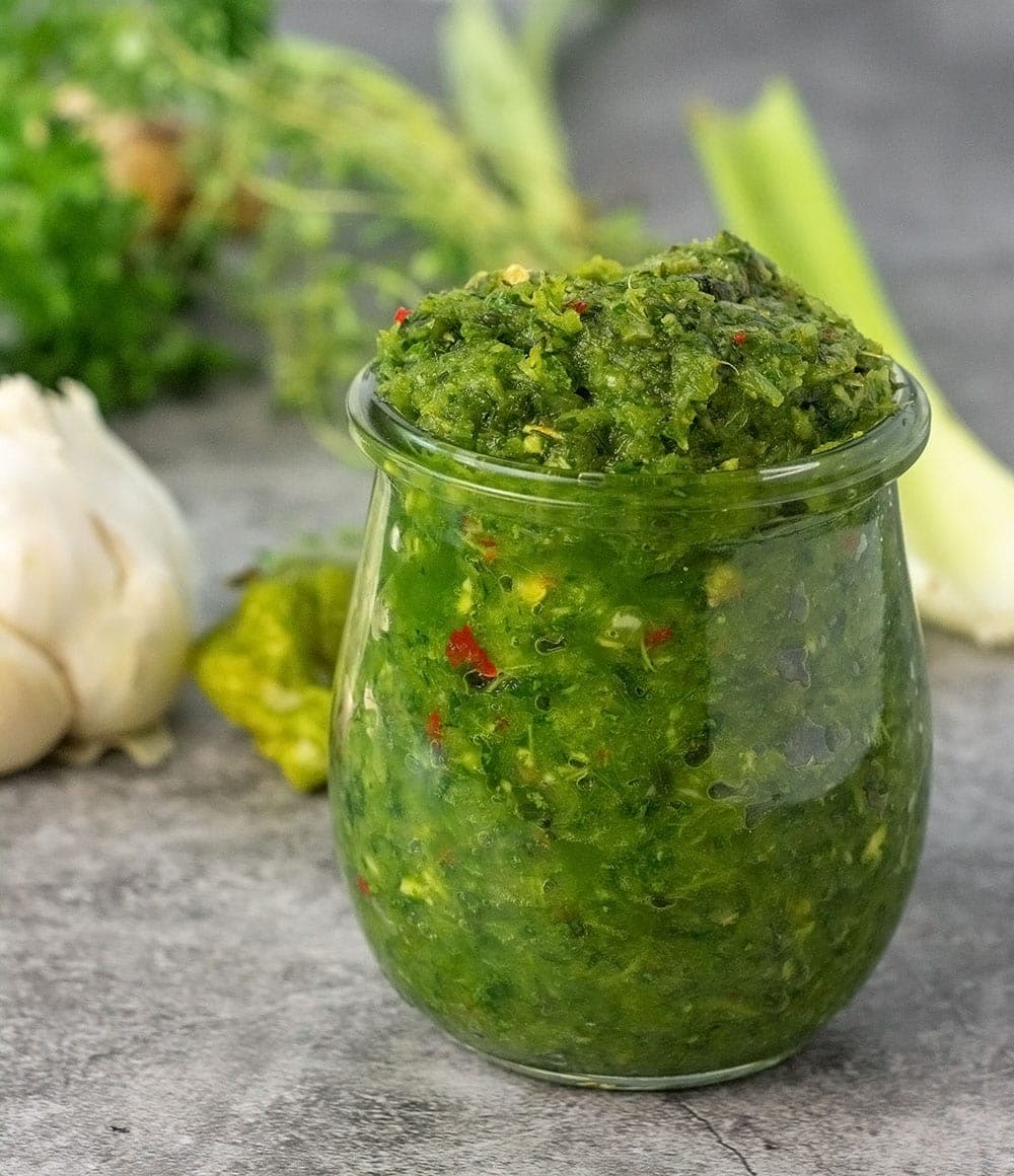 caribbean green seasoning on glass jar on grey background