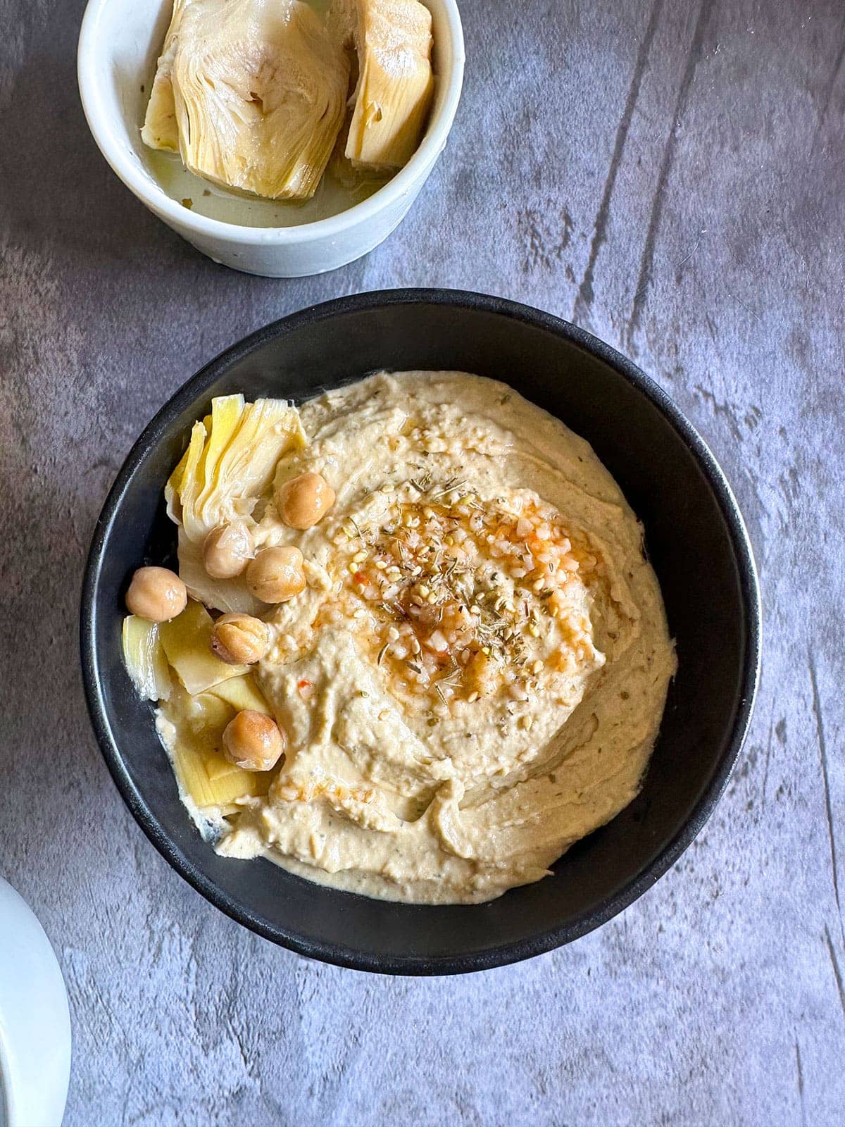 artichoke hummus on a black bowl on grey background