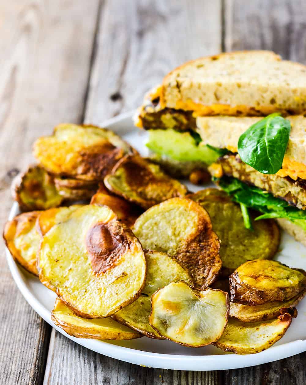 Homemade Baked Potato Chips on white plate on wooden background
