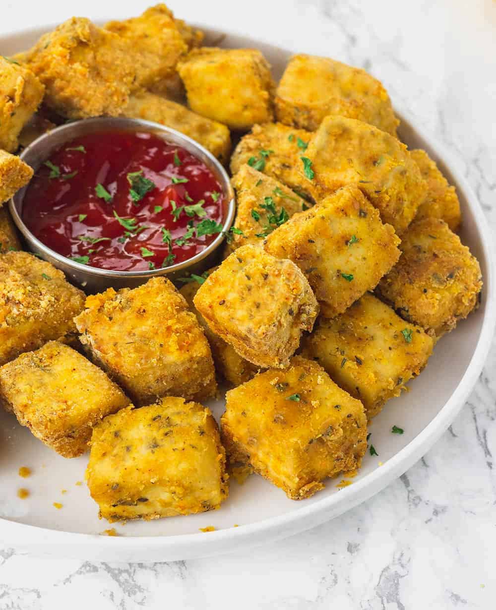 Baked tofu nuggets on white plate on white background