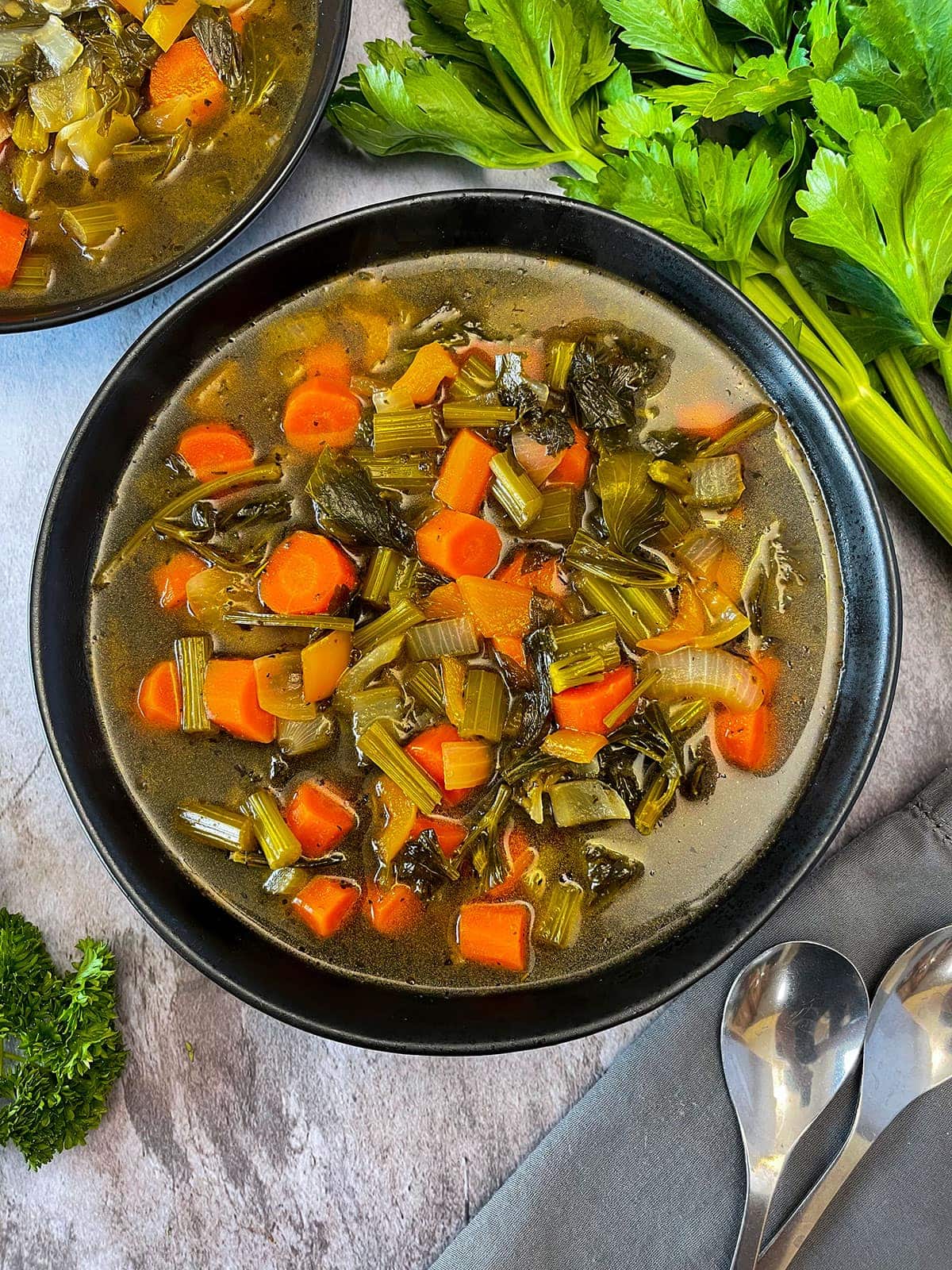 Carrot and Celery Soup in black bowl on grey background