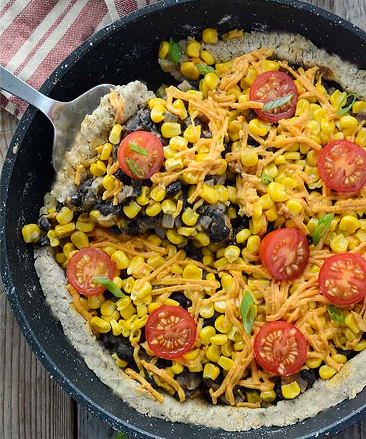 gluten free black bean pizza overlay in a cast iron skillet on a wooden background