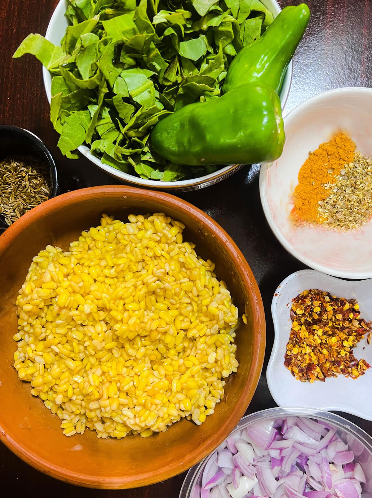 ingredients lentil spinach bhajis on black background in bowls