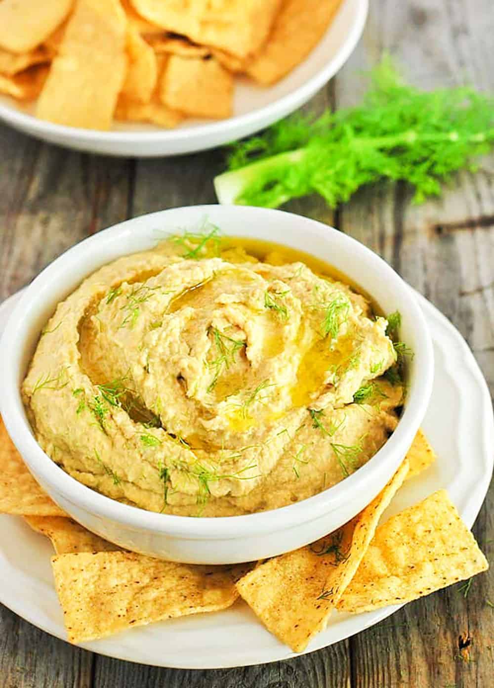 Roasted Fennel Hummus in a white bowl on wooden background.