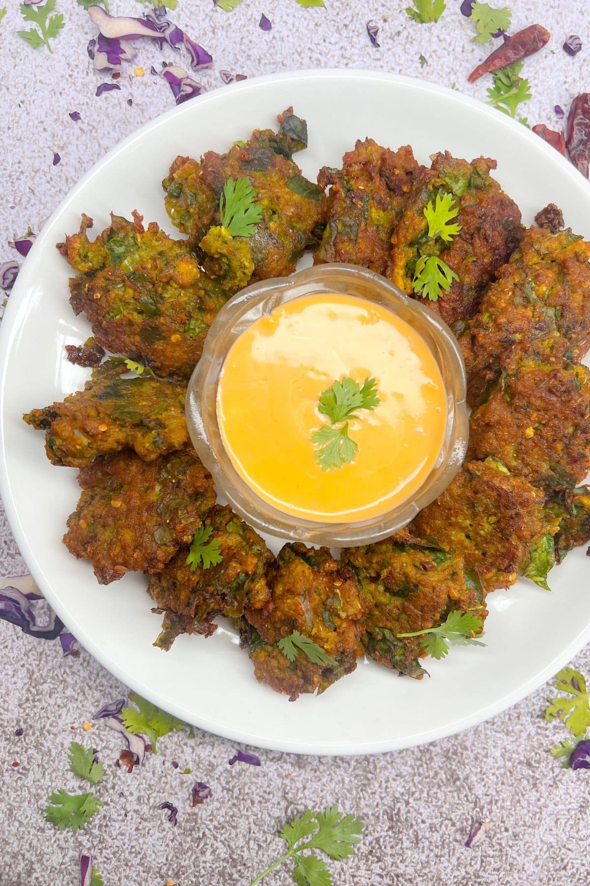 Spinach and yellow lentil bhajis on a white plate on a grey background