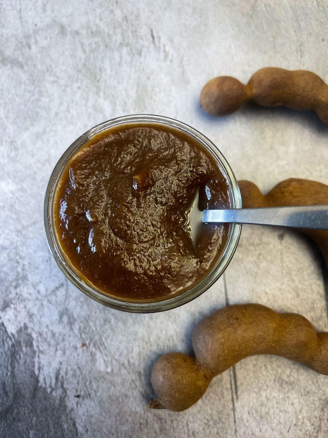 tamarind date chutney in glass jar on grey background.