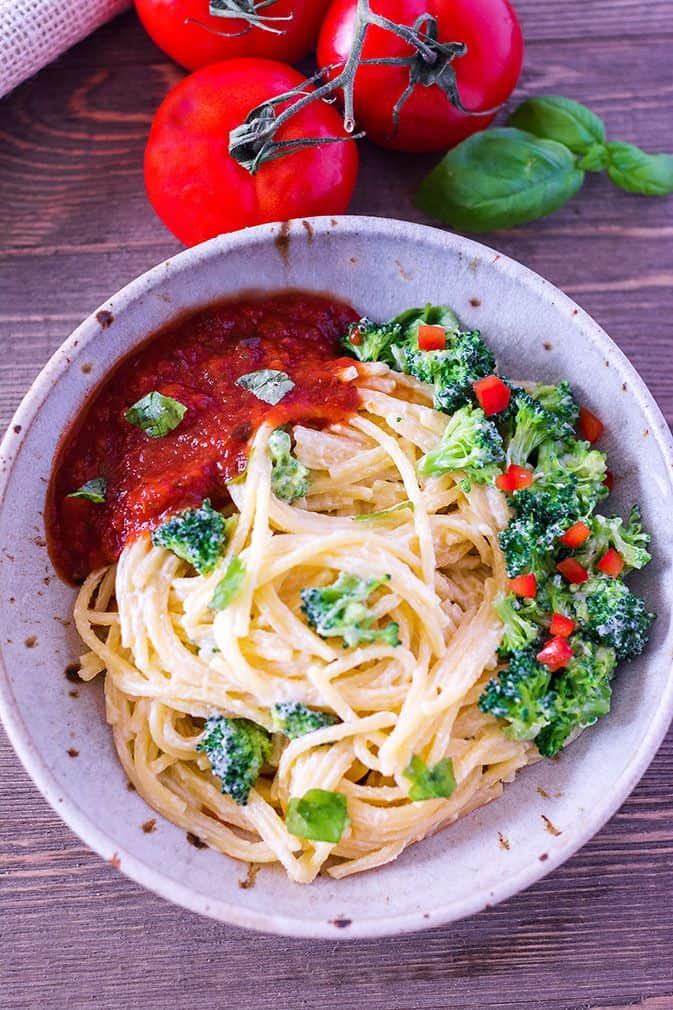 overlay of vegan spaghetti with broccoli in a beige bowl on a wooden background