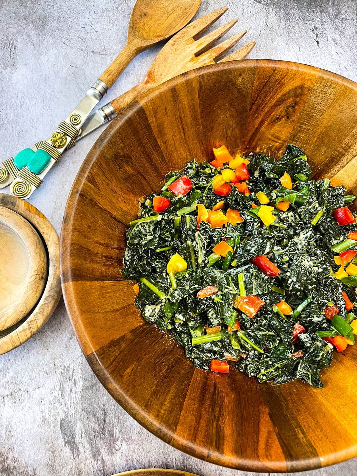 Warm Kale Salad in wooden bowl on grey background