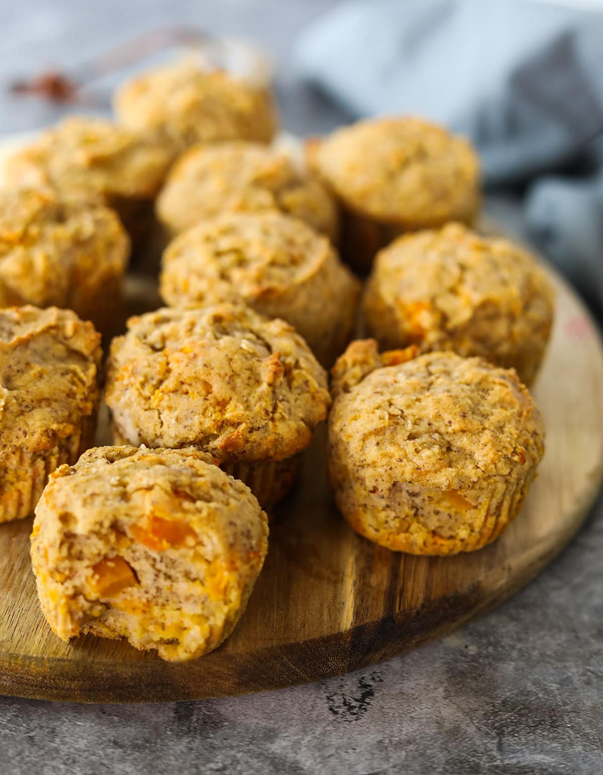 Gluten-free vegan butternut quash muffins on a round cutting board on a grey concrete with a grey apron