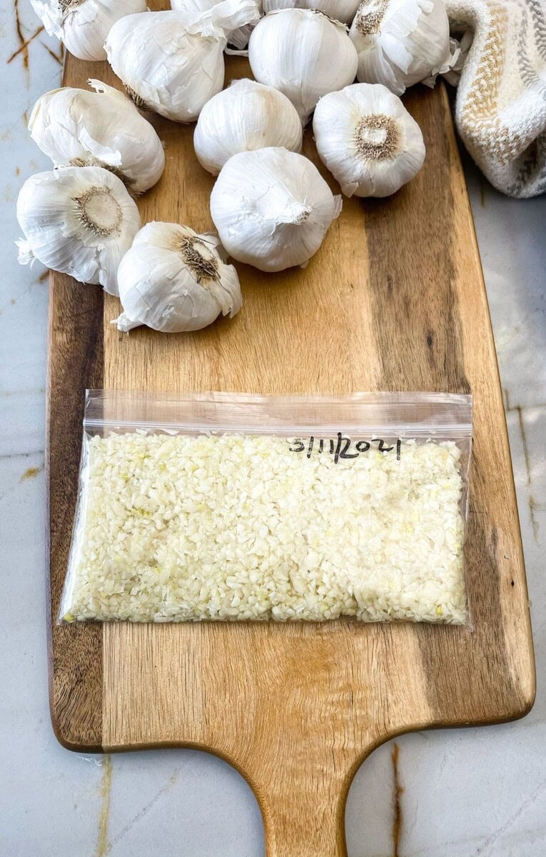 minced garlic in freezer bag on a wooden cutting board