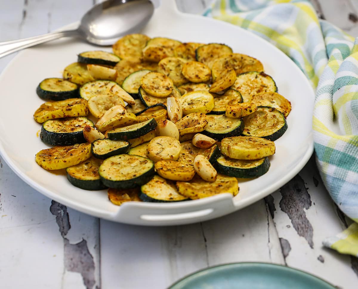 Ovengeroosterde courgette en pompoen op een witte schotel op een witte achtergrond