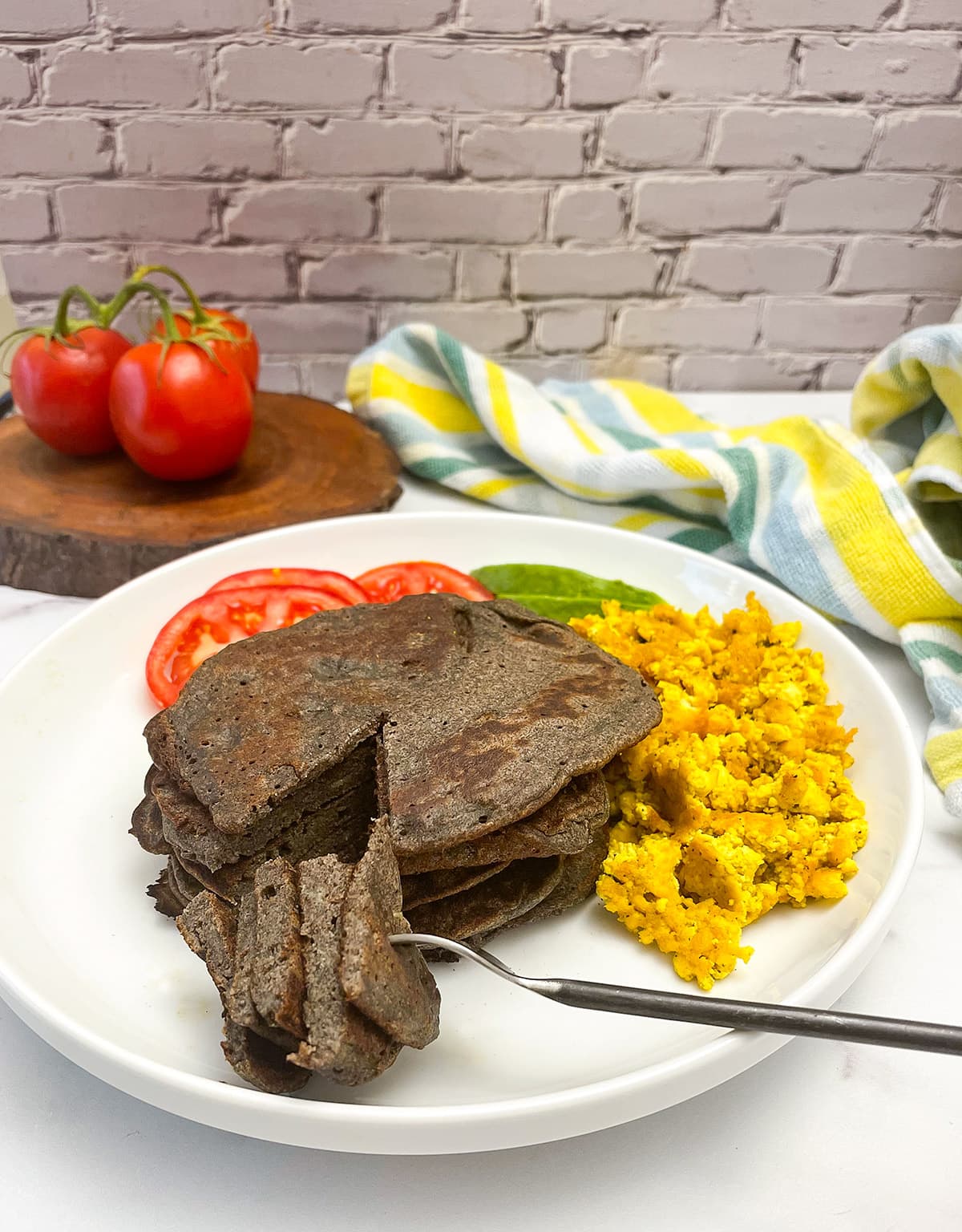 buckwheat pancake on a white plate with tofu scramble on a white background