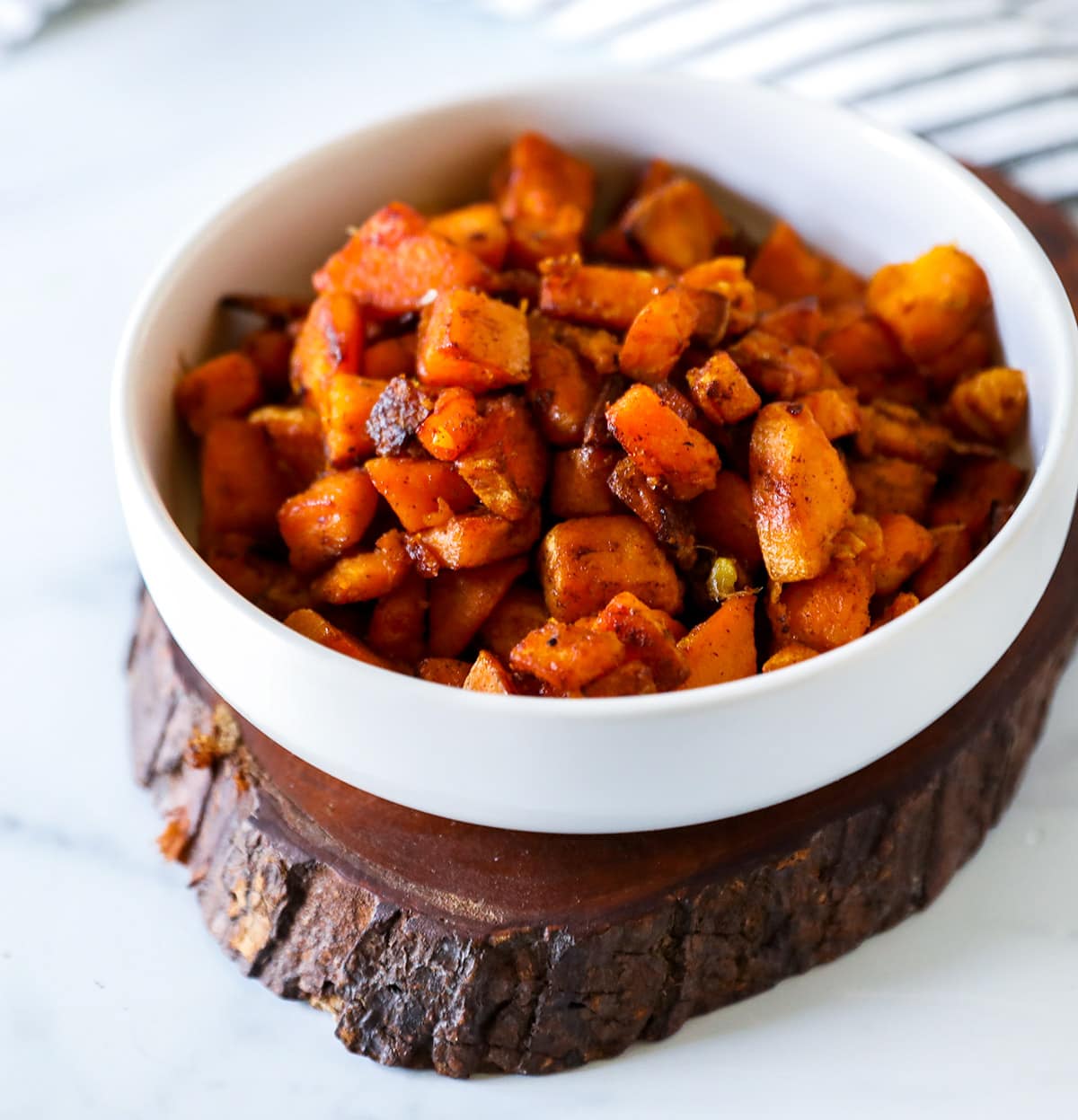 sweet potato skillet in white bowl on wooden cutting board on a white background