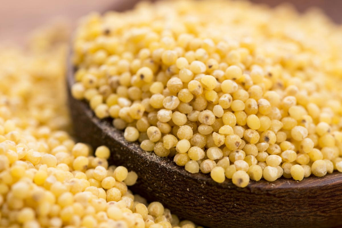 millet groats in and spilling out of wooden bowl