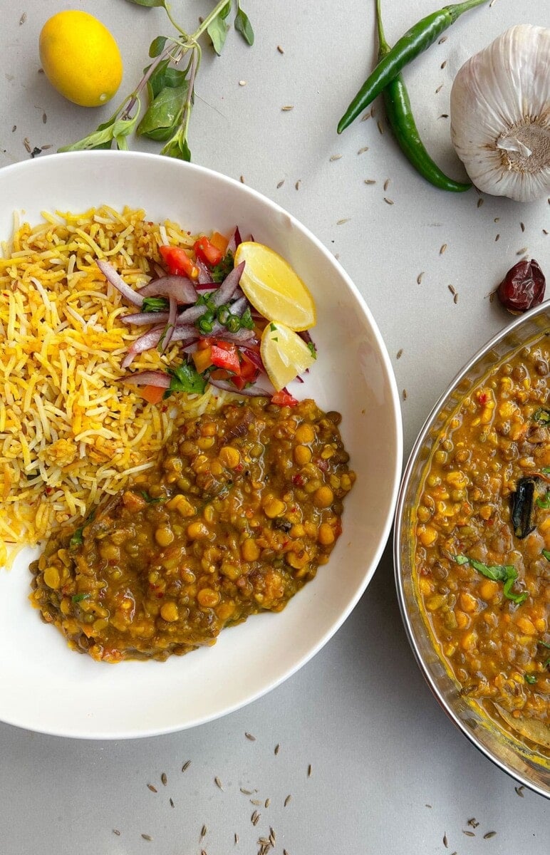 Mixed lentil curry in a white bowl on white background