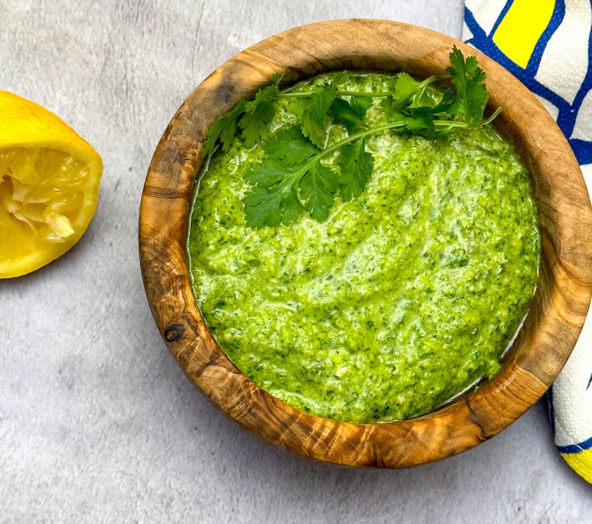 Vegan cilantro pesto in wooden bowl on grey background