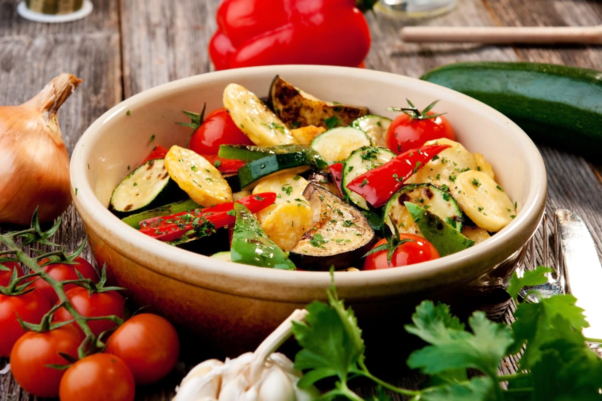 Oven roasted vegetables on wooden background, rustic style