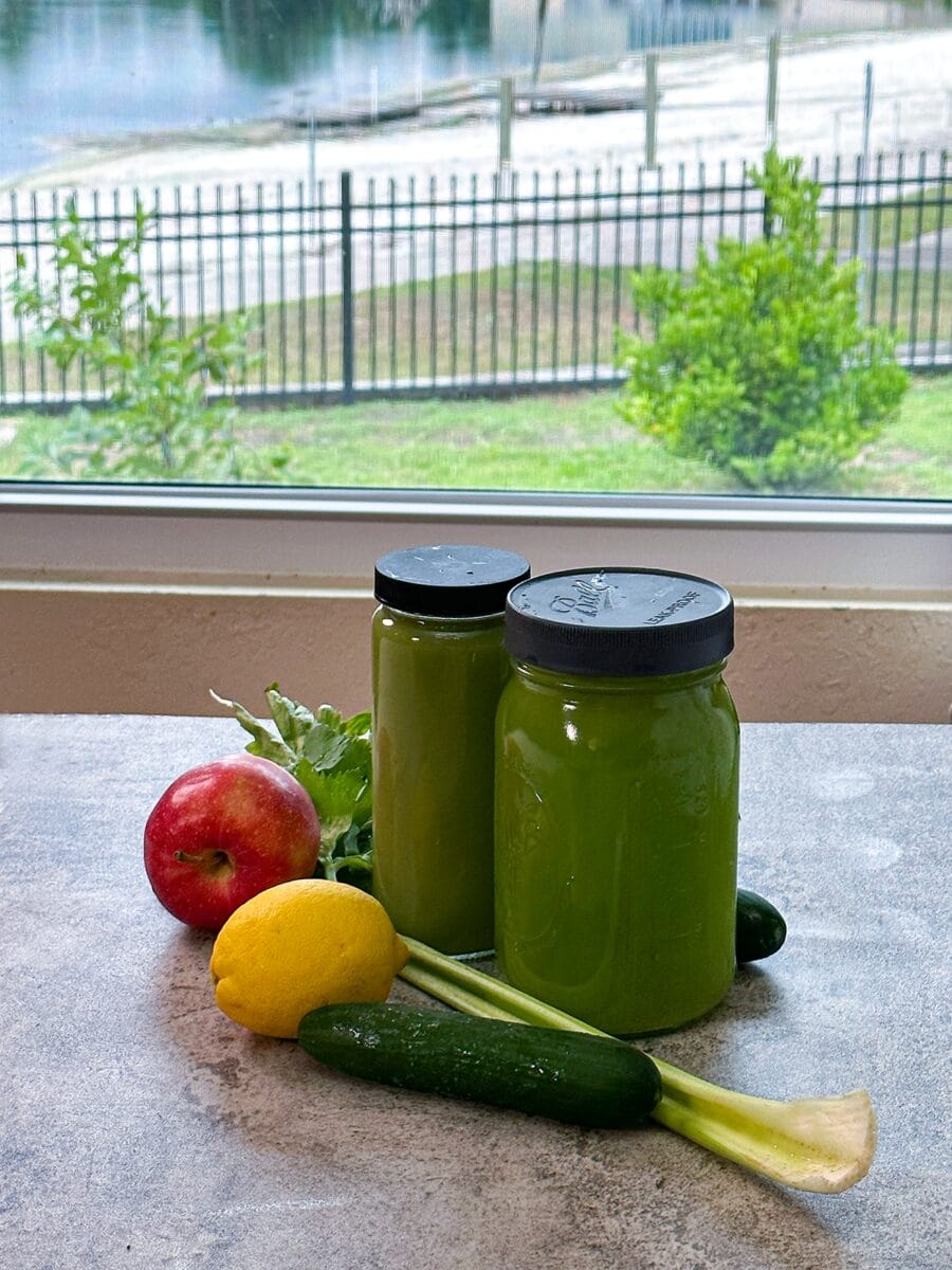 cucumber apple anti-inflammatory juices in bottles on a counter with the background outside